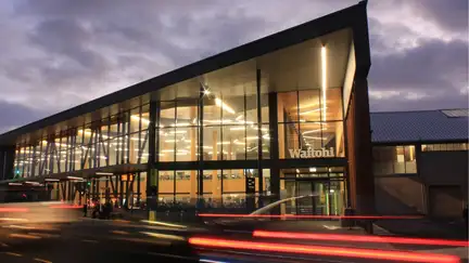 Exterior of Johnsonville Library at night, with the library all lit up and cars rushing past