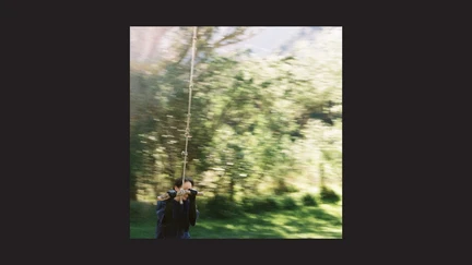 Single art (blurry photograph of a figure in front of trees), on a black background.