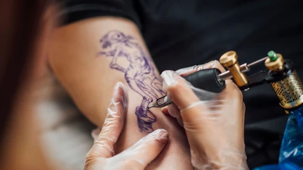 Photo of someone tattooing a person's arm.