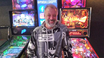 Hamish in front of a row of pinball machines.