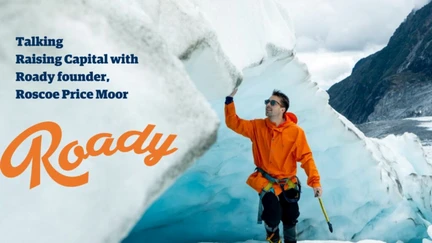 Photo of a person in an orange winter jacket trekking through a glacier.