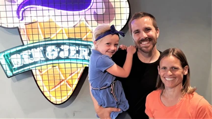 Photo of Nick and Mel in front of a neon Ben and Jerry's sign.