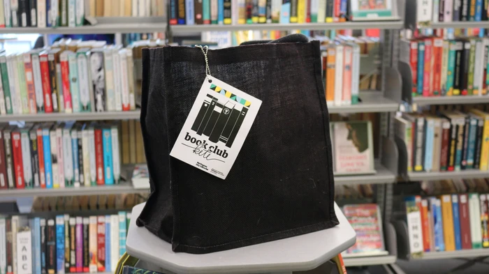 Photo of our Book Club Kete in front of a bookshelf.