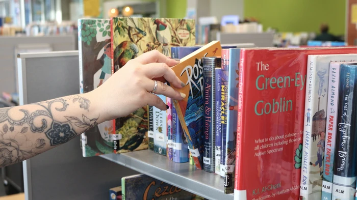 Photo of a hand selecting a book from the shelf.