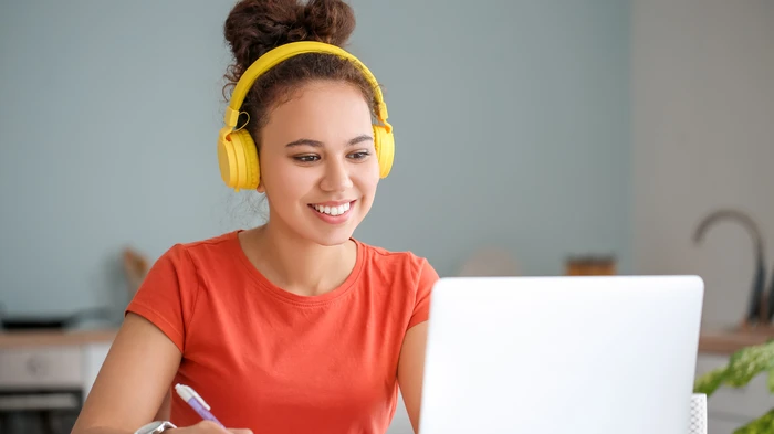 Photo of a person at a laptop with yellow headphones on.