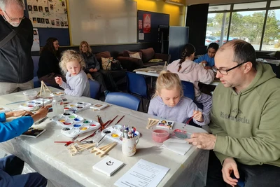 Two tables of tamariki painting on 10cm canvases