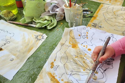 Children use paintbrushes and water coloured with brown paint to make their maps look older.