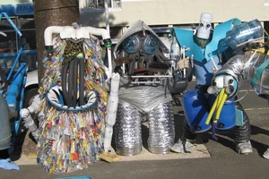 A line of people wearing full body costumes made of recycled materials.