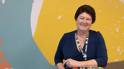 Photo of business librarian Linda Stopforth, in front of a yellow, white and blue patterned wall.