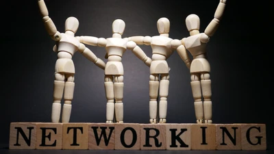 Wooden models representing people, with arms around each other, atop alphabet blocks spelling 'networking'