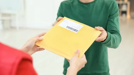 Courier handing a book-sized courier envelope to a library patron