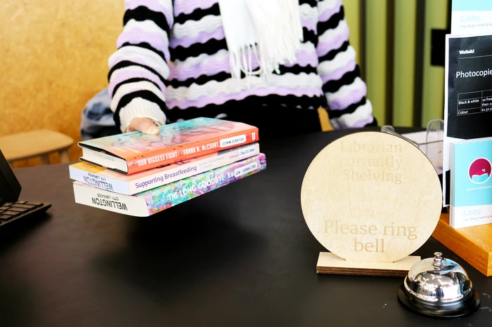 Librarian at a help desk holding books.