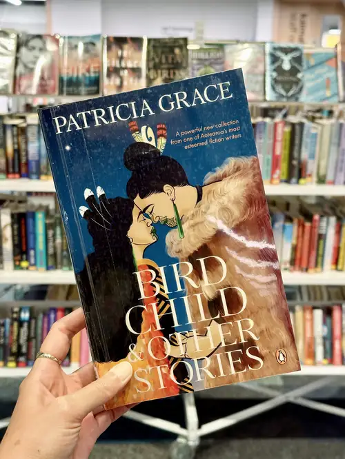 Person holding the book Bird Child & Ohter Stories by Patricia Grace at a library