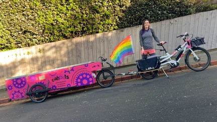 Jade standing alongside her e-bike and e-powered and braked trailer.