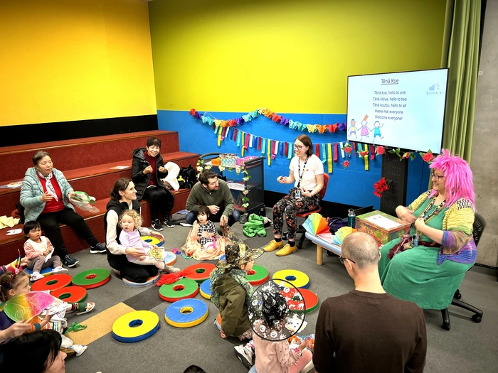 Two librarians, both wearing colourful costumes and wigs, are reading stories to