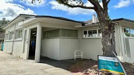 Exterior of Island Bay Library, showing a level entrance and large tree