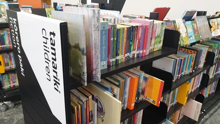 Rows of chapter books sitting on black shelves. A sign at the front reads "Tamariki - children. Kōrero paki - fiction."