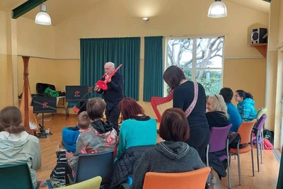 Peter Maunder and Michelle Velvin, both playing bright red instruments, move amongst the audience.