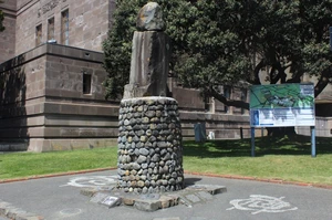 Memorial on a cobblestone plinth, surrounded by grass and a tree on the right