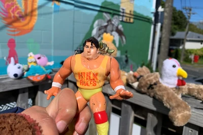 A toy with the body of Hulk Hogan, the head of Superman, and some metallic horns on one shoulder held in front of a row of other toys