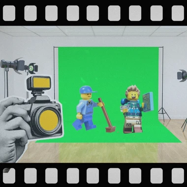 A film negative style border around an image of a camera pointing at two LEGO figures in front of a green screen