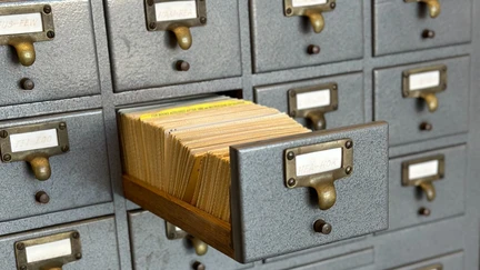 An old card catalogue, with one drawer open displaying yellowed cards