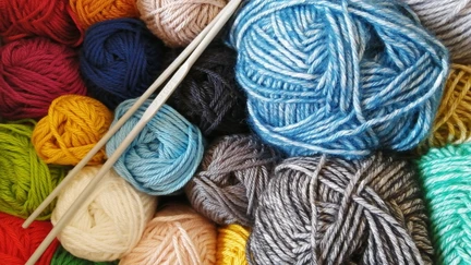 Two crochet hooks laid over a pile of colourful yarn