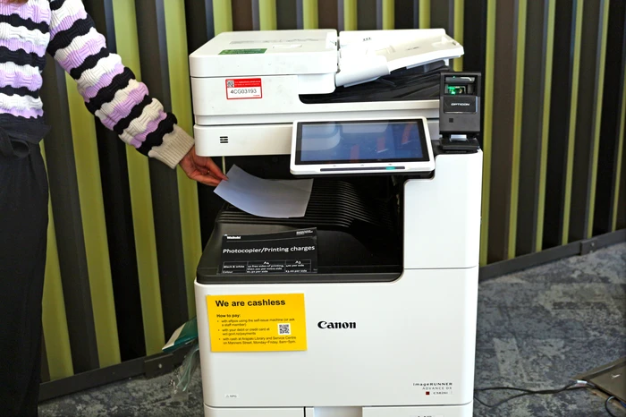 Photo of someone retrieving a piece of paper from one of our printers.