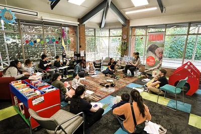 Children sit on the floor while a Zealandia educator reads from a picture book.